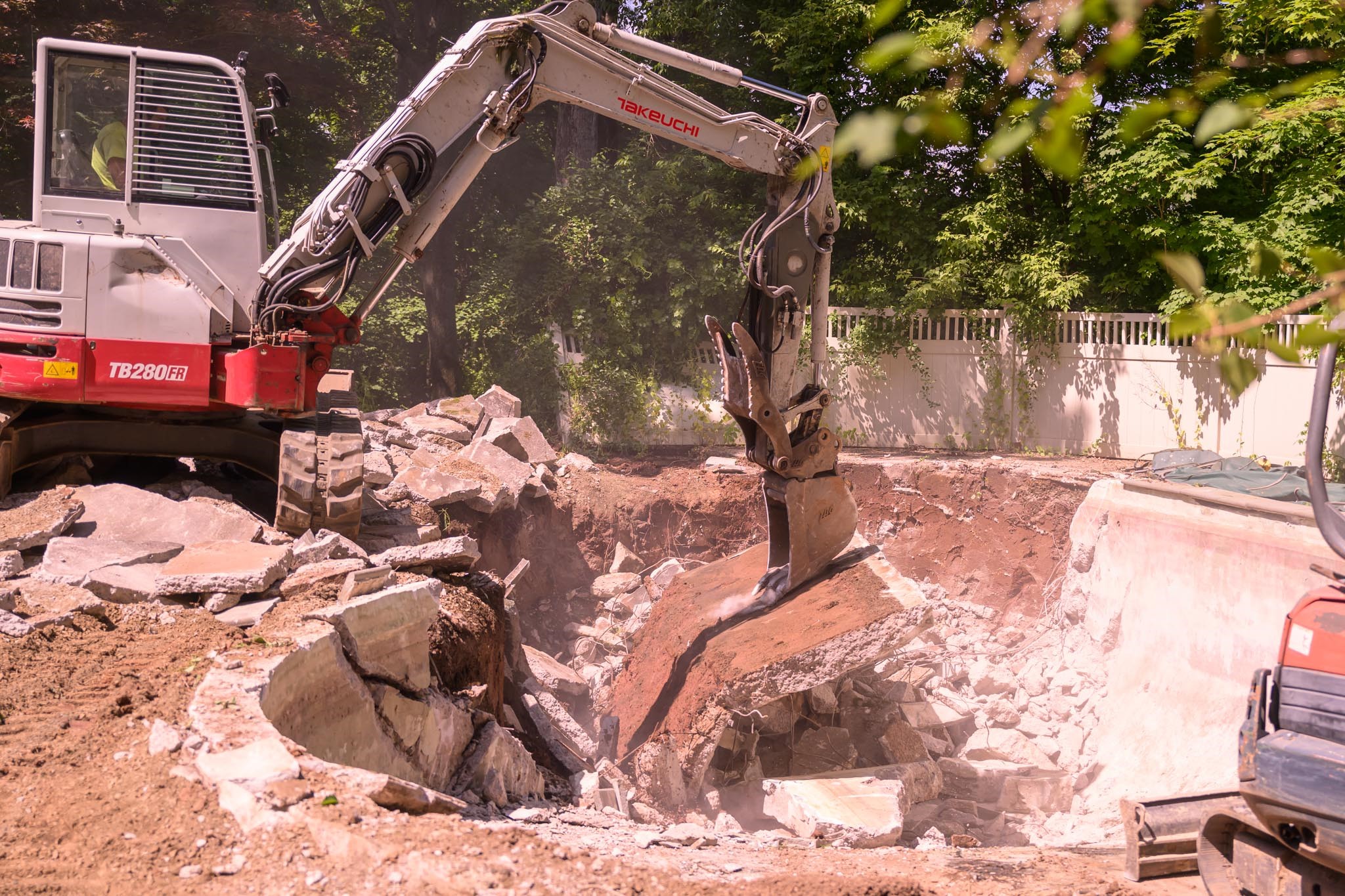 A red and white excavator clearing rubble at a construction site.