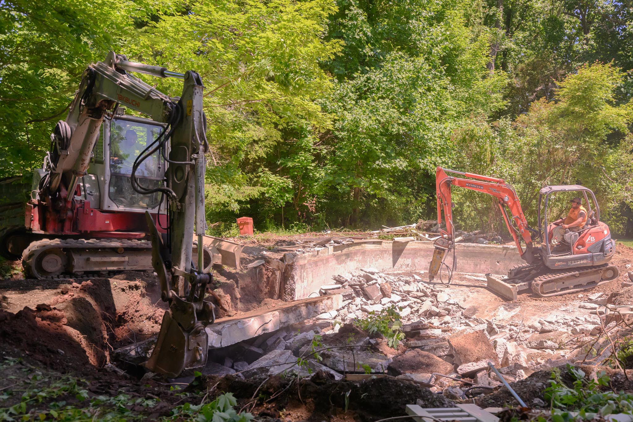 Construction equipment in the woods: A scene showing heavy machinery amidst trees, engaged in construction activities.