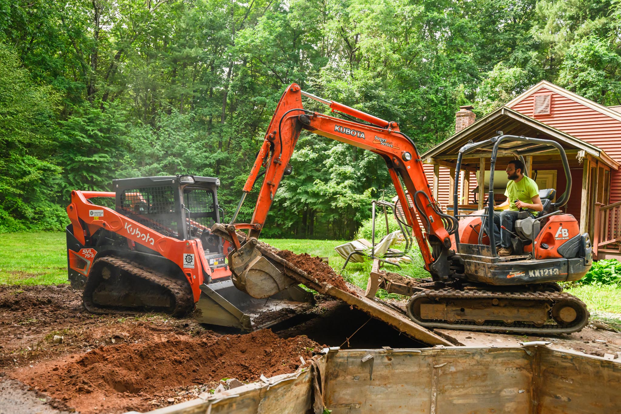 An excavator using its claw attachment to raise cement structure. This technique helps by dropping heavier pieces to fall and break for easier removal.