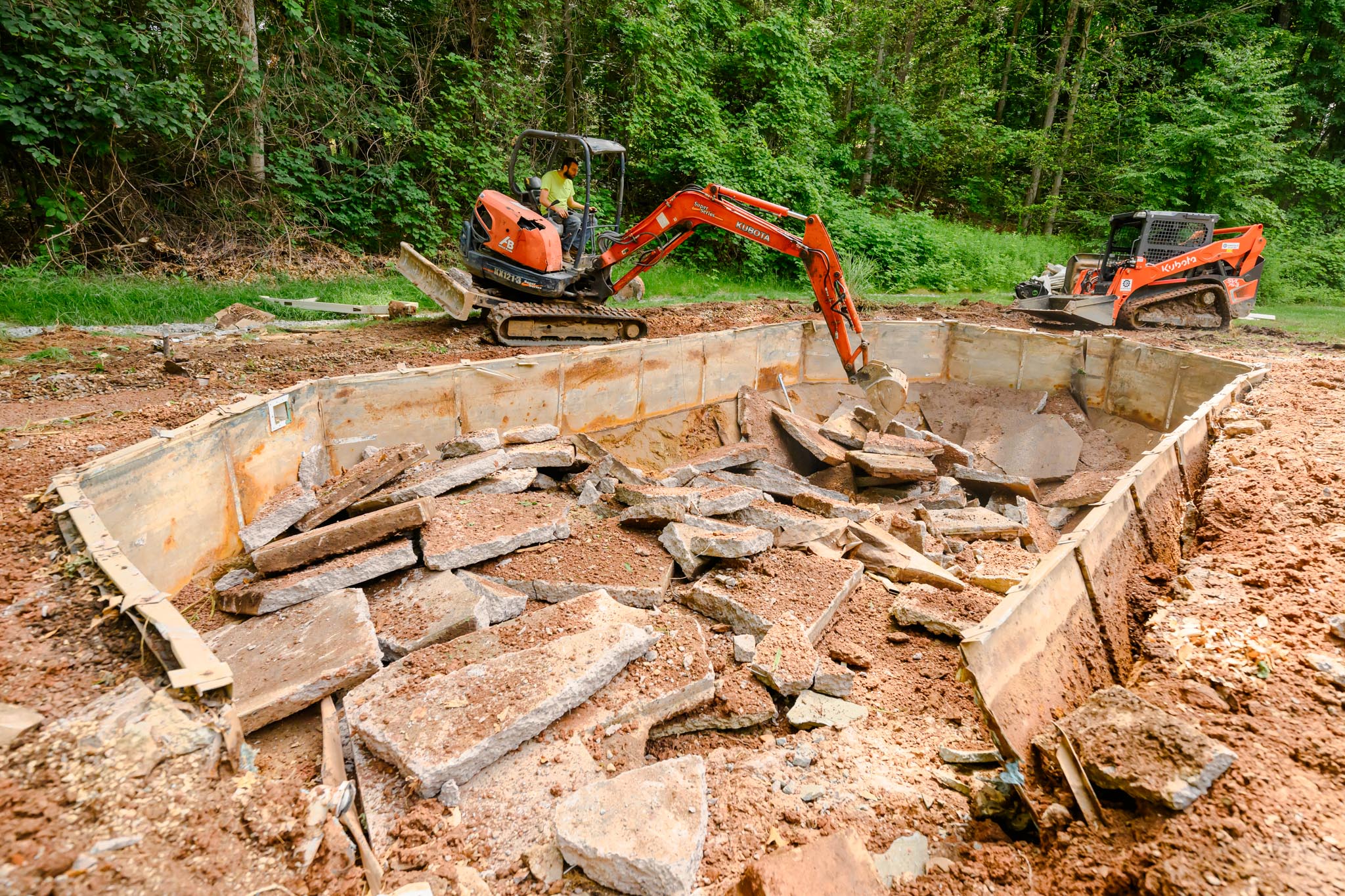 Large cement structure pieces of the pool being carefully stacked in hole to become buried. Glastonbury CT