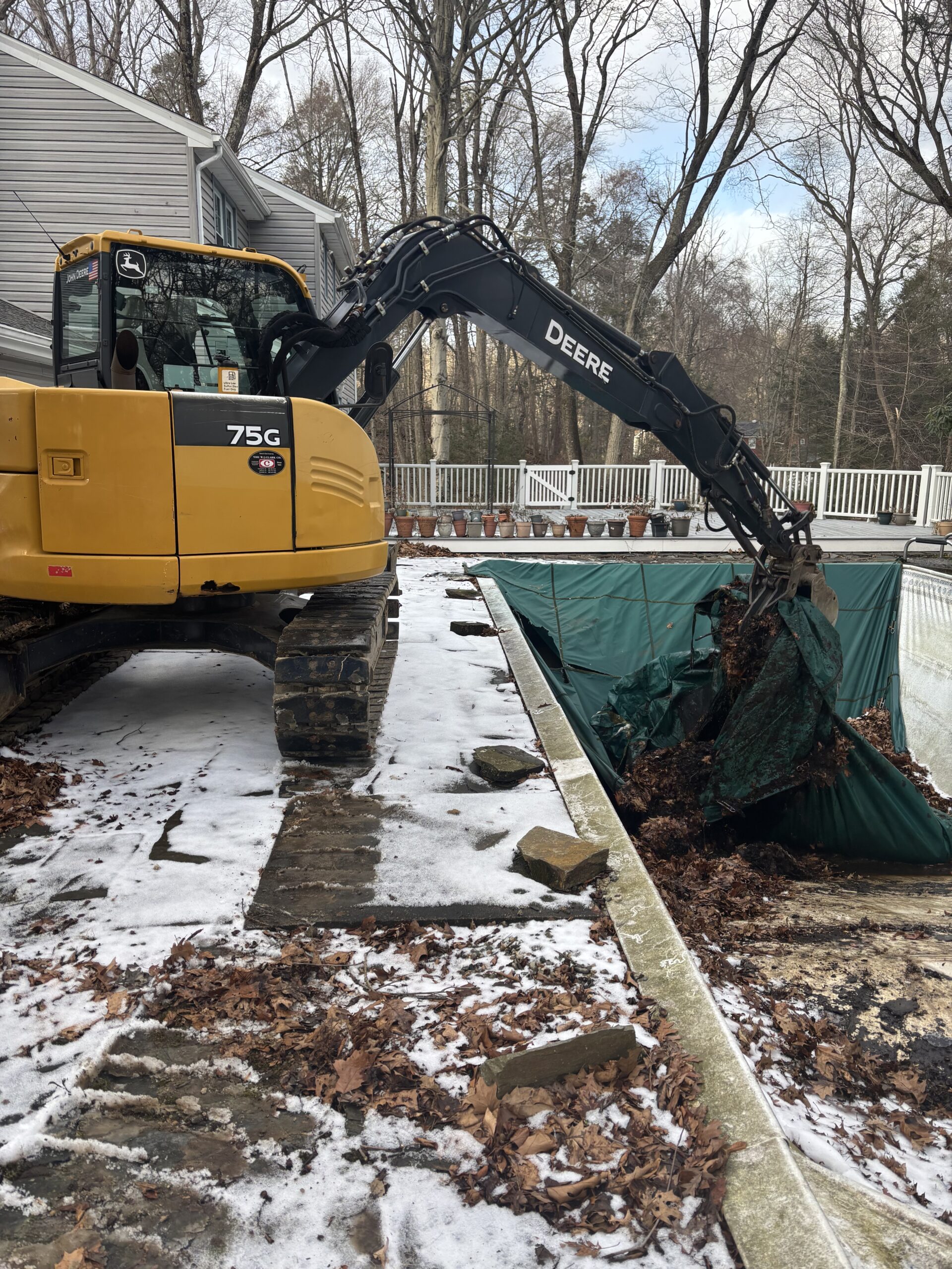 Excavator alongside a swimming pool removing the liner