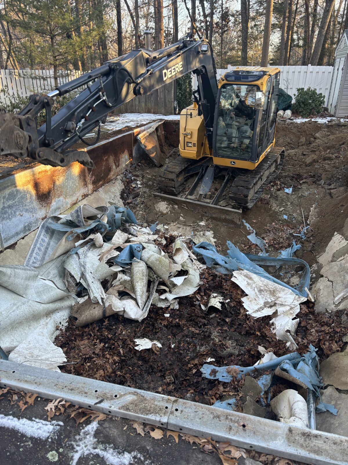 Excavator in a pool removing the walls and liner