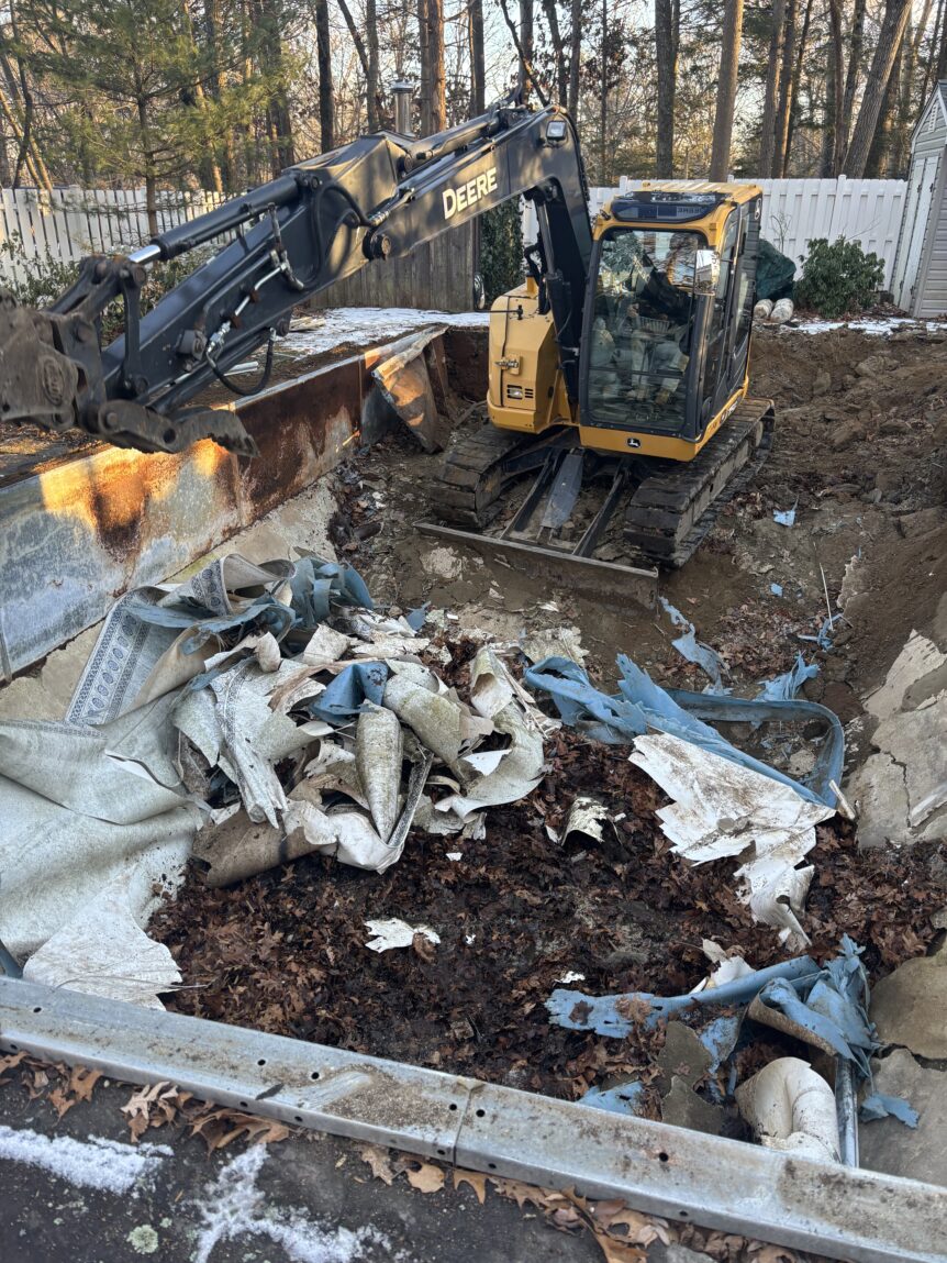 Excavator in a pool removing the walls and liner